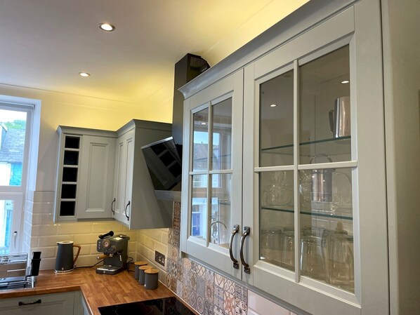 A kitchen with white cabinets, a built-in oven, and a coffee machine.
