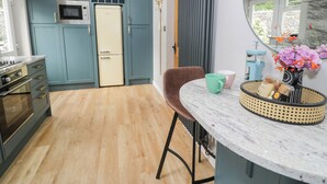 A modern kitchen with teal cabinets, a vintage refrigerator, and a marble countertop. - Pengwern Bach (Llanrwst)