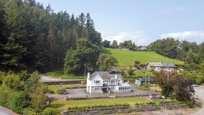 A large house with a stone foundation, a large front porch, and a well-maintained lawn. - Pengwern Bach (Llanrwst)