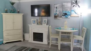 Una habitación con chimenea, televisión y comedor con sillas y mesa.