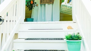 Una escalera con un letrero de 'WELCOME', plantas en macetas y un farol colgante.