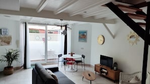 Una sala de estar moderna con un sofá, una mesa de comedor con sillas, un televisor y una escalera.