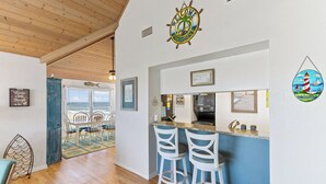 A kitchen area with a bar, white bar stools, and a sign indicating beach rules. - Luxury, Ocean Front, Cargo Lift, 3rd Floor Penthouse KD0003 (Kill Devil Hills)