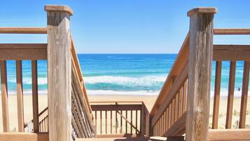 A wooden staircase leading to a beach with a clear view of the ocean.