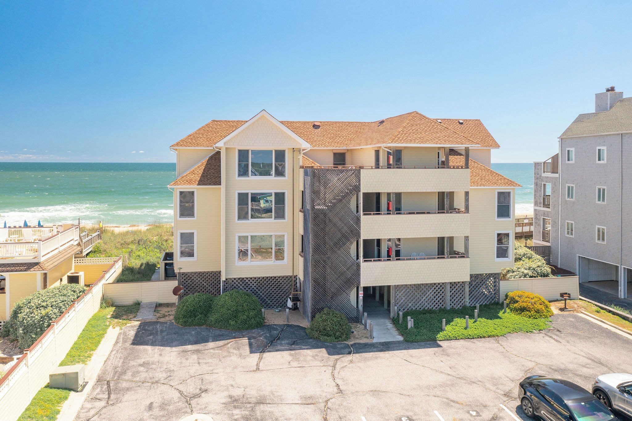 A multi-story building with a balcony, located near a beach with a clear view of the ocean.