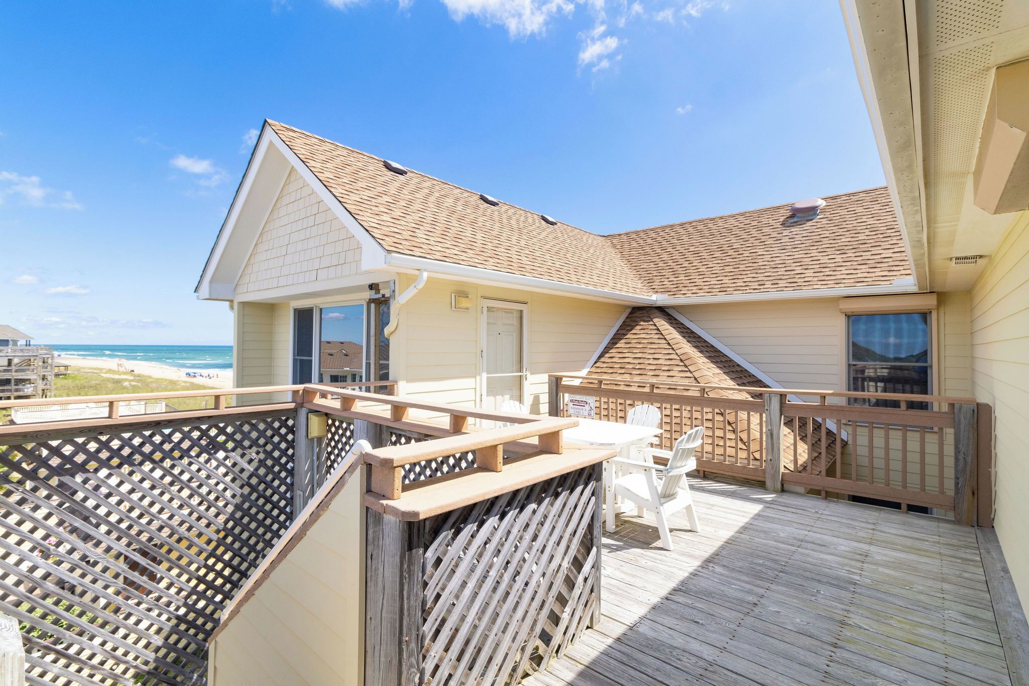 A beach house with a deck, a covered patio, and a view of the ocean.