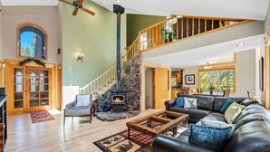 Amplia sala de estar con chimenea, sofá de cuero y una escalera que conduce a un nivel superior.