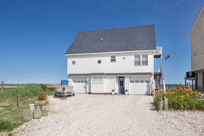 A two-story house with a garage, a boat in front, and a flag on the roof. - Coves Point by Seaside Vacations & Sales (Greenbackville)