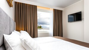 Une chambre d’hôtel avec un lit, une télévision et une fenêtre avec des rideaux.