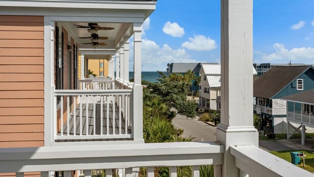 A coastal house with a balcony, a ceiling fan, and a view of the ocean. - Crabby Paddy: Short Walk To Beach, Sunset Views (Garden City Beach)