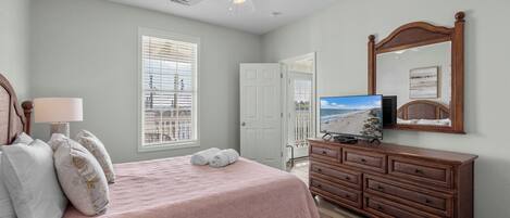 Une chambre à coucher comprenant un lit, une commode, un téléviseur et un ventilateur de plafond.