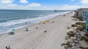 A beach with a pier in the background, sandy beach, and buildings on the right. - Crabby Paddy: Short Walk To Beach, Sunset Views (Garden City Beach)