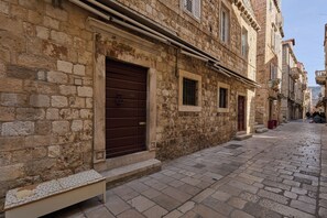 A stone building with a large wooden door and a bench in front.