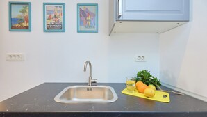A kitchen with a sink, a countertop, and three framed posters on the wall. - Room Annette - One Bedroom Apartment, Sleeps 2 (Dubrovnik)