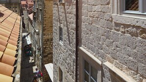 A narrow street with stone buildings, a clear blue sky, and a few pedestrians. - Room Annette - One Bedroom Apartment, Sleeps 2 (Dubrovnik)
