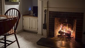 Una habitación acogedora con chimenea, una mesa de comedor y un televisor sobre la chimenea.