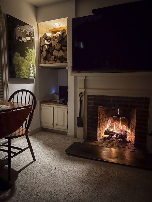 A cozy room with a fireplace, a dining table, and a TV mounted above the fireplace.
