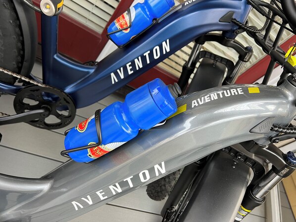 Un vélo de la marque « AVENTON », avec deux gourdes bleues fixées au cadre.