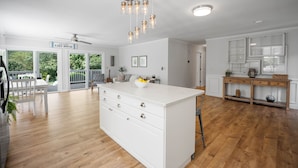 Eine geräumige Küche mit Kochinsel, Holzboden und Deckenventilator.