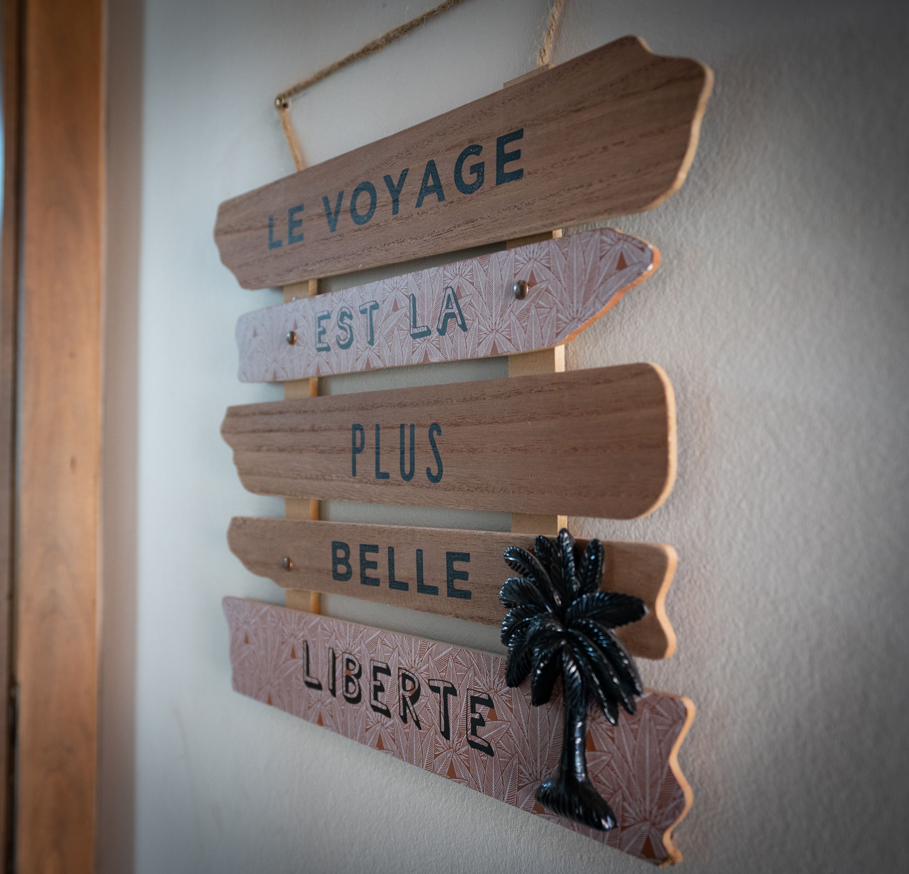 Puinen kyltti, jossa lukee: »LE VOYAGE EST LA PLUS BELLE LIBERTE», on kiinnitetty seinään.