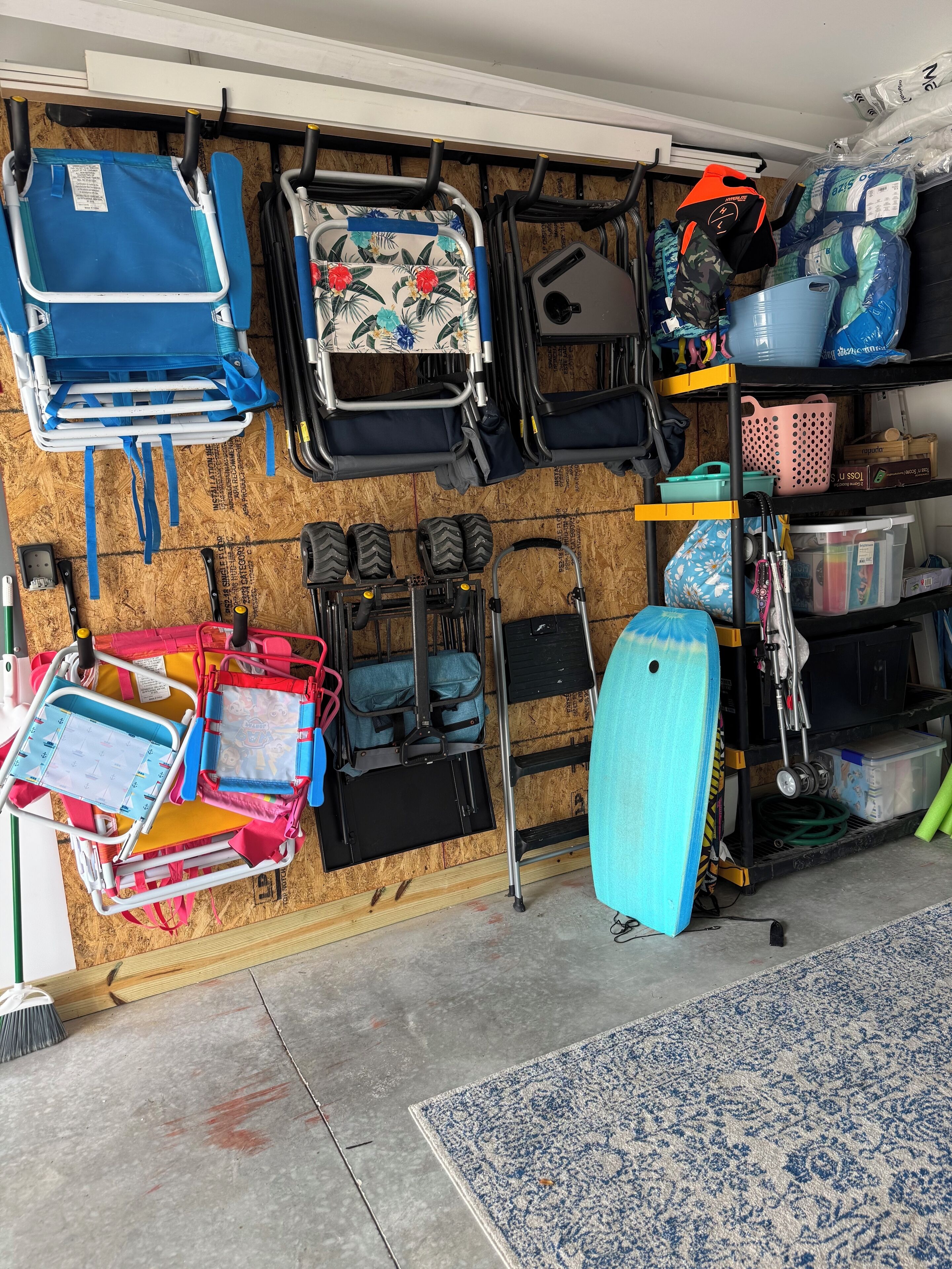 A storage area with various items including a blue suitcase, a red and yellow cart, and multiple bags and containers.