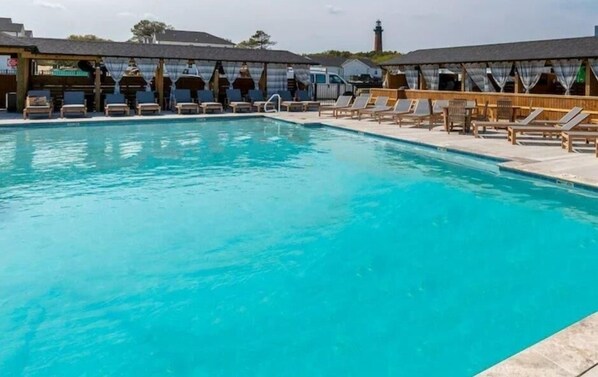 Une piscine entourée d’aires de repos abritées, avec des chaises longues et des parasols.