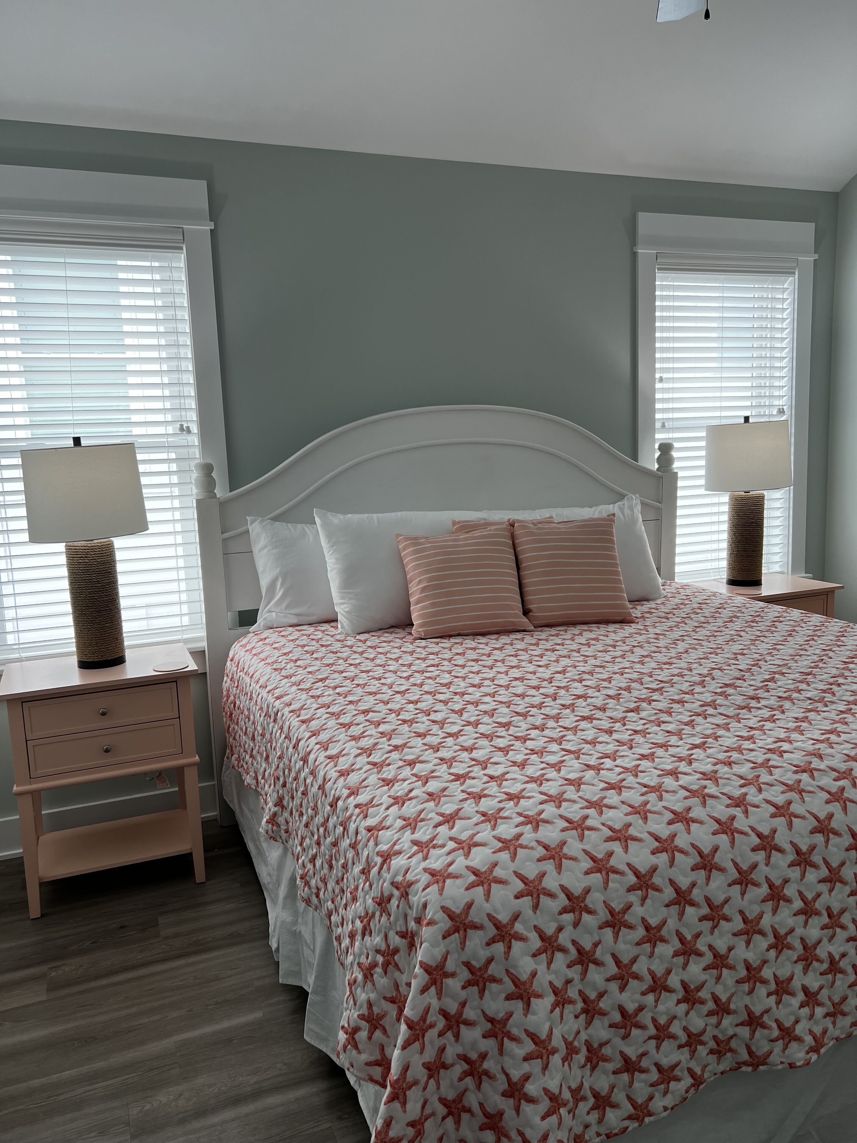 Une chambre à coucher avec un lit, deux tables de chevet et une fenêtre avec des stores.