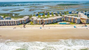 A coastal hotel with multiple buildings, a beach, and a swimming pool. - A Wave From it All | Oceanfront Community Pool! (North Topsail Beach)