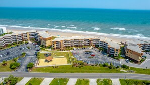 A coastal hotel with multiple buildings, a parking lot, and a beach view. - A Wave From it All | Oceanfront Community Pool! (North Topsail Beach)