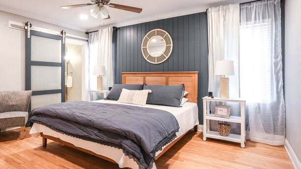 A bedroom with a bed, a nightstand, a chair, a ceiling fan, and a window with curtains. - ⛵️Coastal Retreat at Tech Terrace 3/2 Remodeled 2 Kings (Lubbock)