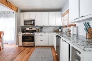 Een moderne keuken met witte kasten, roestvrijstalen apparatuur en een marmeren aanrecht.