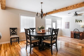 A dining area with a round table, four chairs, a chandelier, and wooden flooring. - ❤️Heart of Med District Lit’l Sister 3/2 Remodeled (Lubbock)