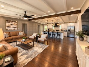 A spacious living area with a sofa set, a coffee table, and a dining area with bar stools. - Heart of Medical District 4BR Home | Walk to Tech & Med Ctr (Lubbock)