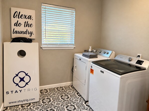 A laundry room with a washing machine, dryer, and a wall-mounted sign.