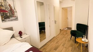 A hotel room with a bed, a chair, a small table, a mirror, and a painting of the Eiffel Tower. - Hotel Kronenkurve (Bergkamen)