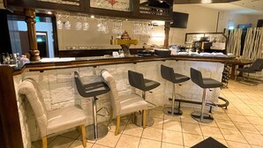 A bar area with a marble countertop, four bar stools, and a wine rack above. - Hotel Kronenkurve (Bergkamen)