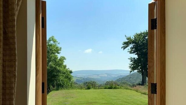 An open doorway leading to a grassy outdoor area with a clear view of a hilly landscape.
