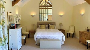 A bedroom with a large bed, two bedside tables, a dresser, a bench, and a mirror above the bed.