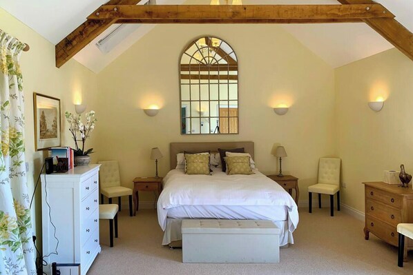 A bedroom with a large bed, two bedside tables, a dresser, a bench, and a mirror above the bed. - 1 Bed Cottage - Sleeps 2 - Parking - Wifi (Minehead)