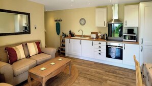 A compact living space with a sofa, a coffee table, a kitchen area including a microwave, oven, and cabinets.