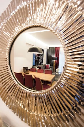 A dining area with a round mirror, a wooden table, and red chairs. - Acropolis Panoramic View Exclusive Apartment | 3 Falirou str 11742 Athens (Athens)
