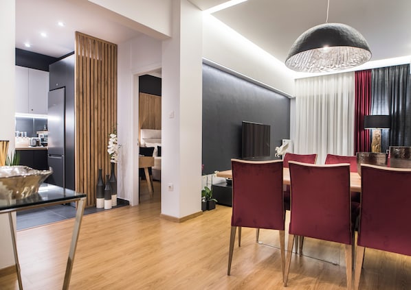 A modern kitchen with a refrigerator, wooden panel wall, and a dining area with a table and chairs.