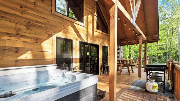 Een houten chalet met een jacuzzi, terras en propaantank.