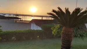 Une plage avec une jetée, des bateaux et un coucher de soleil.