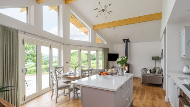 A spacious kitchen with a large island, wooden beams, and a built-in stove. - Pen Bryn (Ruthin)