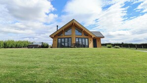 A two-story wooden house with large windows and a sloped roof, surrounded by a well-maintained lawn. - Pen Bryn (Ruthin)