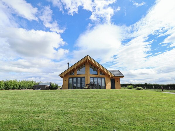 A two-story wooden house with large windows and a sloped roof, surrounded by a well-maintained lawn. - Pen Bryn (Ruthin)