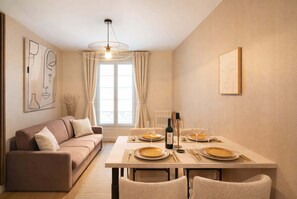A dining area with a table set for four, a sofa, and artwork on the walls.