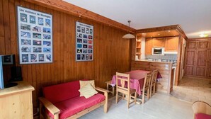 Ein Holzinnenraum mit einem roten Sofa, einem Esstisch mit Stühlen und einer Küchenzeile.