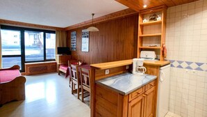 Ein gemütliches Zimmer mit Holzwänden, einer Küchenzeile mit Marmorarbeitsplatte und einem Essbereich mit rotem Tischlein.